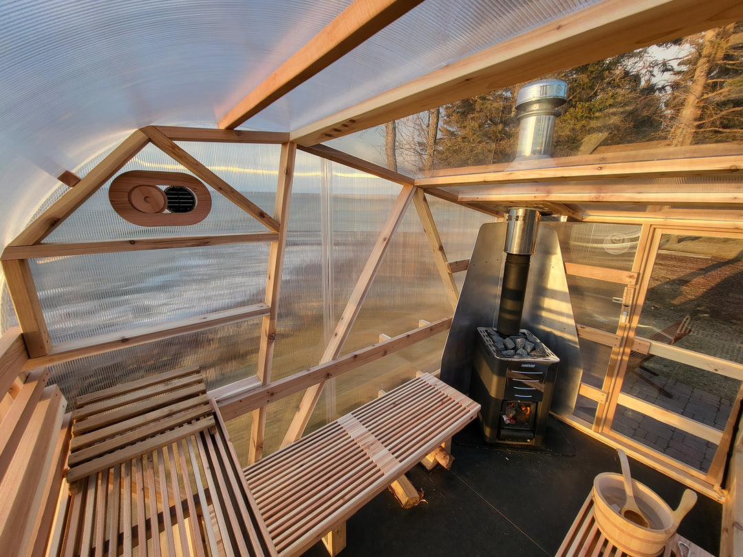Interior view of NorthUp Curve XL sauna. View of lakeside landscape and Harvia sauna stove.