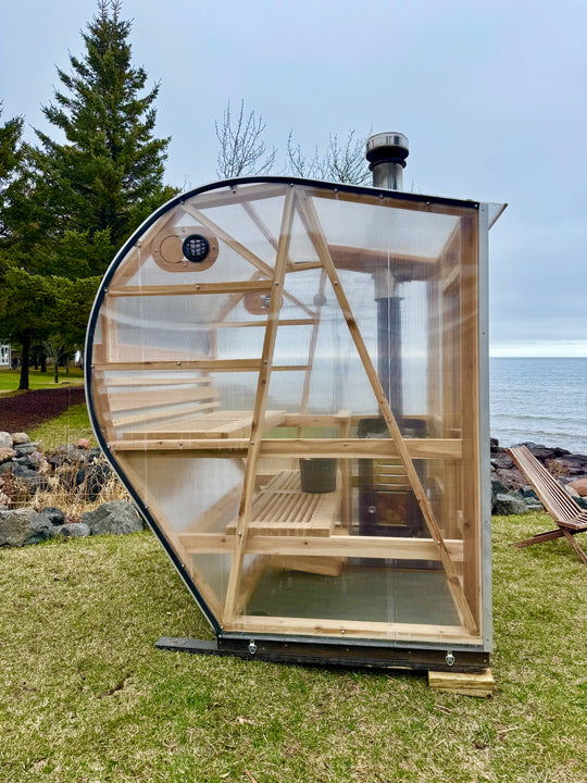 NorthUp curve installed lakeside. Visual of harvia woodfired stove through transparent sauna siding.