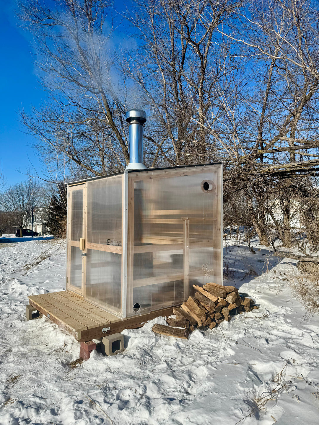 Exterior side view of NorthUp core sauna on a snowy landscape.