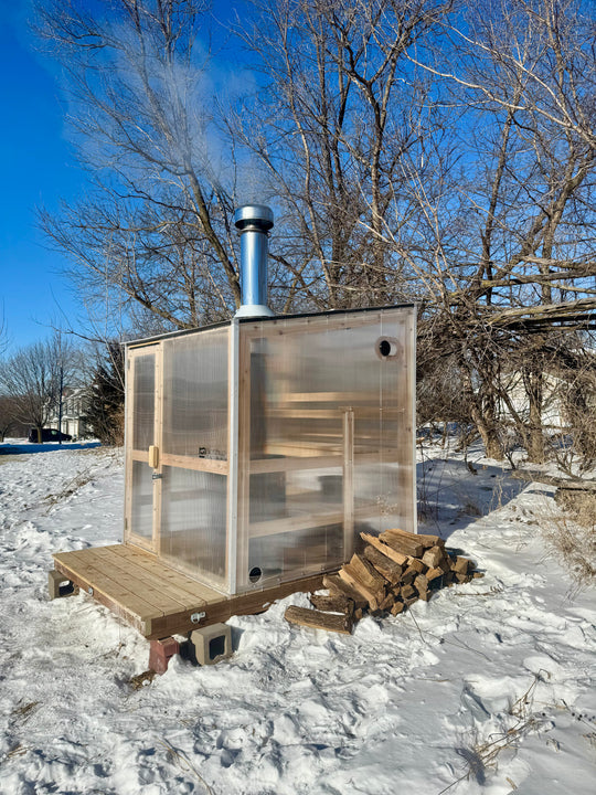 Exterior side view of NorthUp core sauna on a snowy landscape.