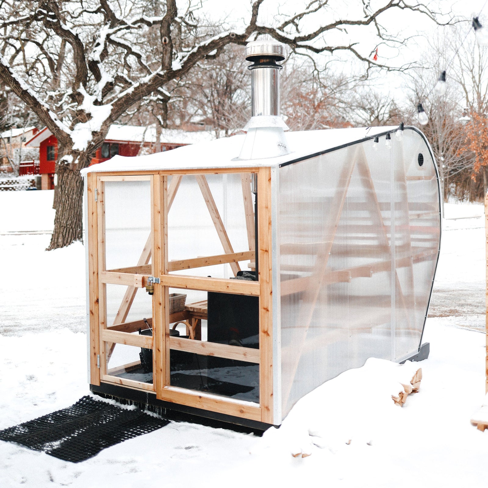NorthUp XL Curve sauna view from exterior of see through panels on front. Sitting on snowy landscape with a tree in the background.