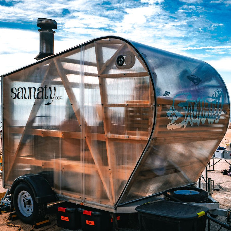 NorthUp XL Mobile sauna trailer parked at a beach. Saunaty logo on side showing a commercial business using a Northup.
