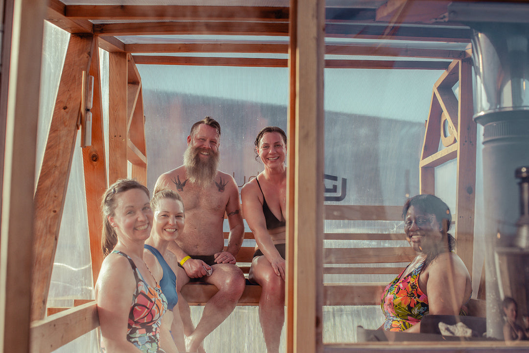 Group of smiling people in bathing suits inside of a transparent NorthUp Sauna XL.